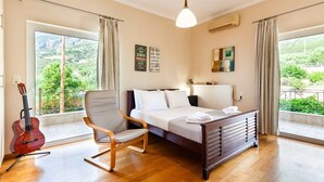 Un dormitorio con cama, una silla, una guitarra y vistas al verde exterior.