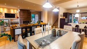 Una sala de estar moderna con comedor, televisor y una escalera que lleva a la cocina.