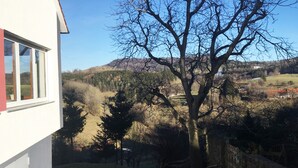 Ein Haus mit Blick auf einen Baum und eine hügelige Landschaft.