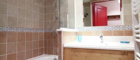 Un baño con tocador de madera, bañera blanca y ducha.