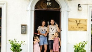 A family standing at the entrance of a building with a sign reading "VILLA VICINI". - Glamping at an Agriturismo in the Vineyard (Ortezzano)