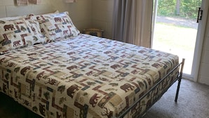 A bedroom with a large bed, a window with curtains, and a view of the outdoors.