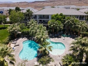 Un resort con area piscina, palme e un edificio a più piani con balconi.