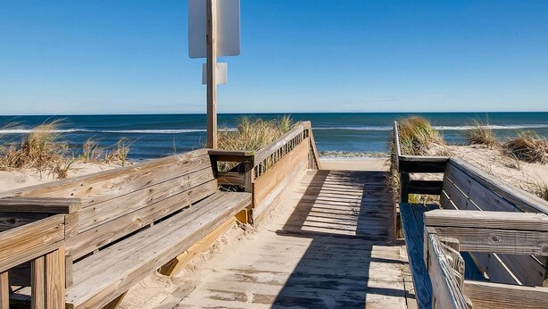 Un muelle de madera que conduce a una playa, con una vista despejada del océano.