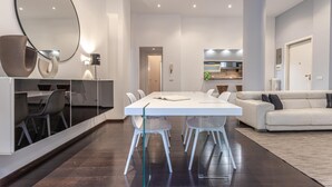 Ein modernes Wohnzimmer mit einem weißen Sofa, einem Esstisch mit Stühlen und einer Küchenzeile im Hintergrund.