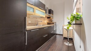 Eine moderne Küche mit dunklen Schränken, einer Holztischplatte und einem kleinen runden Tisch mit einer Pflanze.