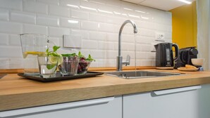 A modern kitchen with a stainless steel sink, a coffee maker, and a tray with glasses of water and fruit.