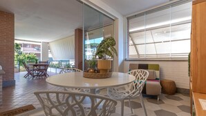 A modern outdoor seating area with a round table and white chairs, a potted plant, and a brick wall. - Kitty Apartment   to visit S. Pietro (ROMA)