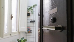 Ovi, jossa on metallinen kahva, ikkuna, jonka karmit ovat valkoiset, ja patteri ikkunan alla.