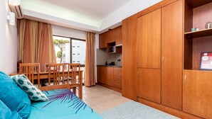 Un espacio habitable compacto con sofá, mesa de comedor y kitchenette.