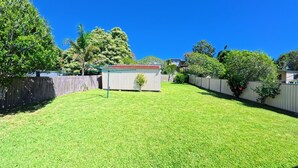 A backyard with a shed, a wooden fence, and trees. - Perfect location close to beach's, town centre and the golf course (South West Rocks)