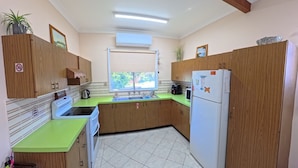 A compact kitchen with wooden cabinets, a green countertop, a sink, a stove, and a refrigerator. - Perfect location close to beach's, town centre and the golf course (South West Rocks)