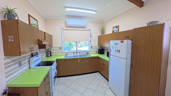 A compact kitchen with wooden cabinets, a green countertop, a sink, a stove, and a refrigerator. - Perfect location close to beach's, town centre and the golf course (South West Rocks)