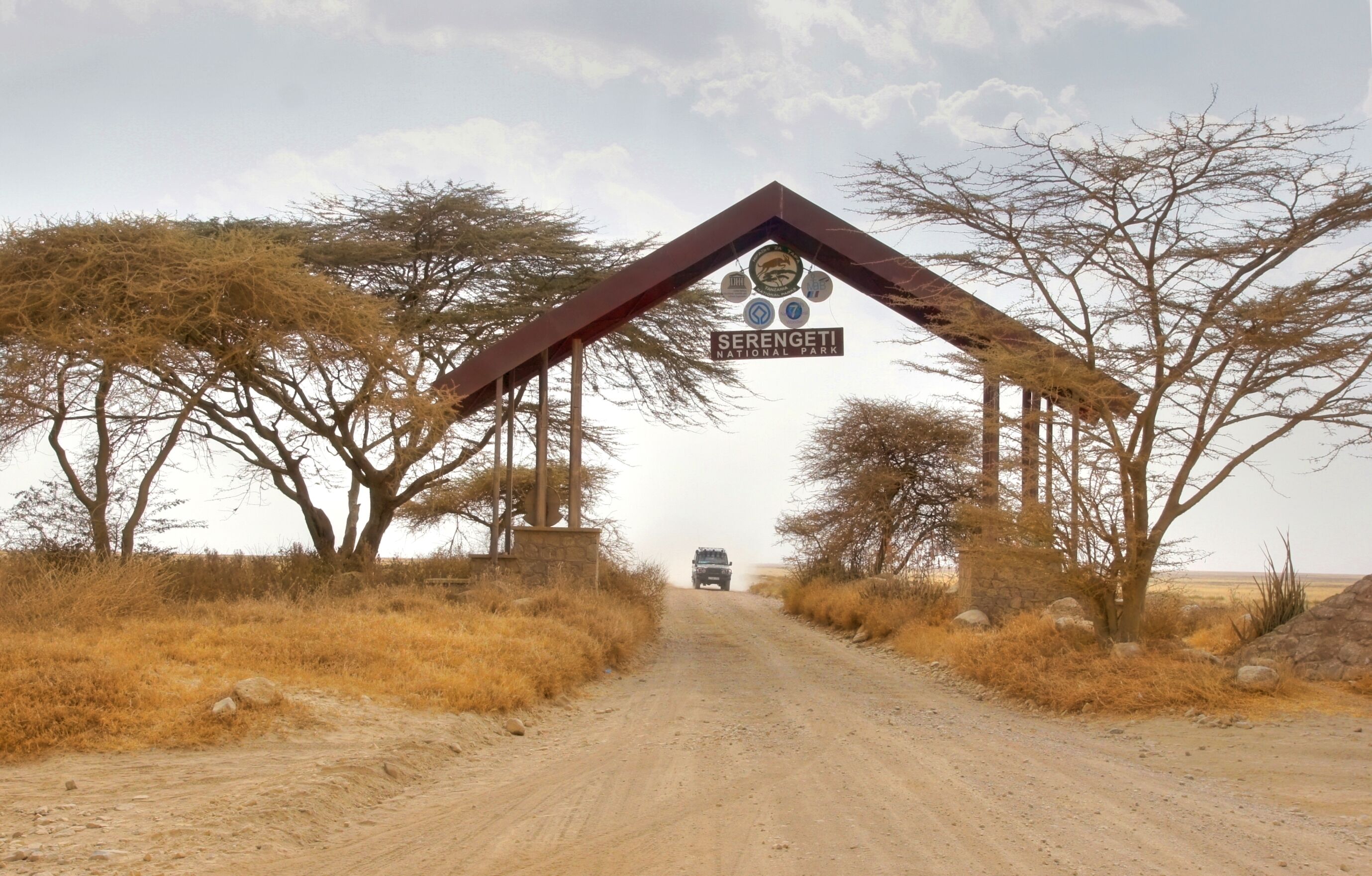 Een onverharde weg naar een bord met daarop Serengeti Nationaal Park.
