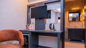 A modern kitchen with a flat-screen TV, a coffee machine, and a wine bottle on the counter. - Zara Suit (Istanbul)
