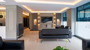 A modern lobby with a sofa, a large painting, and a reception desk. - Zara Suit (Istanbul)