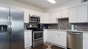 Una cocina moderna con gabinetes blancos, electrodomésticos de acero inoxidable y salpicadero de azulejos.