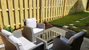 Un patio con muebles de mimbre y una cerca de madera.