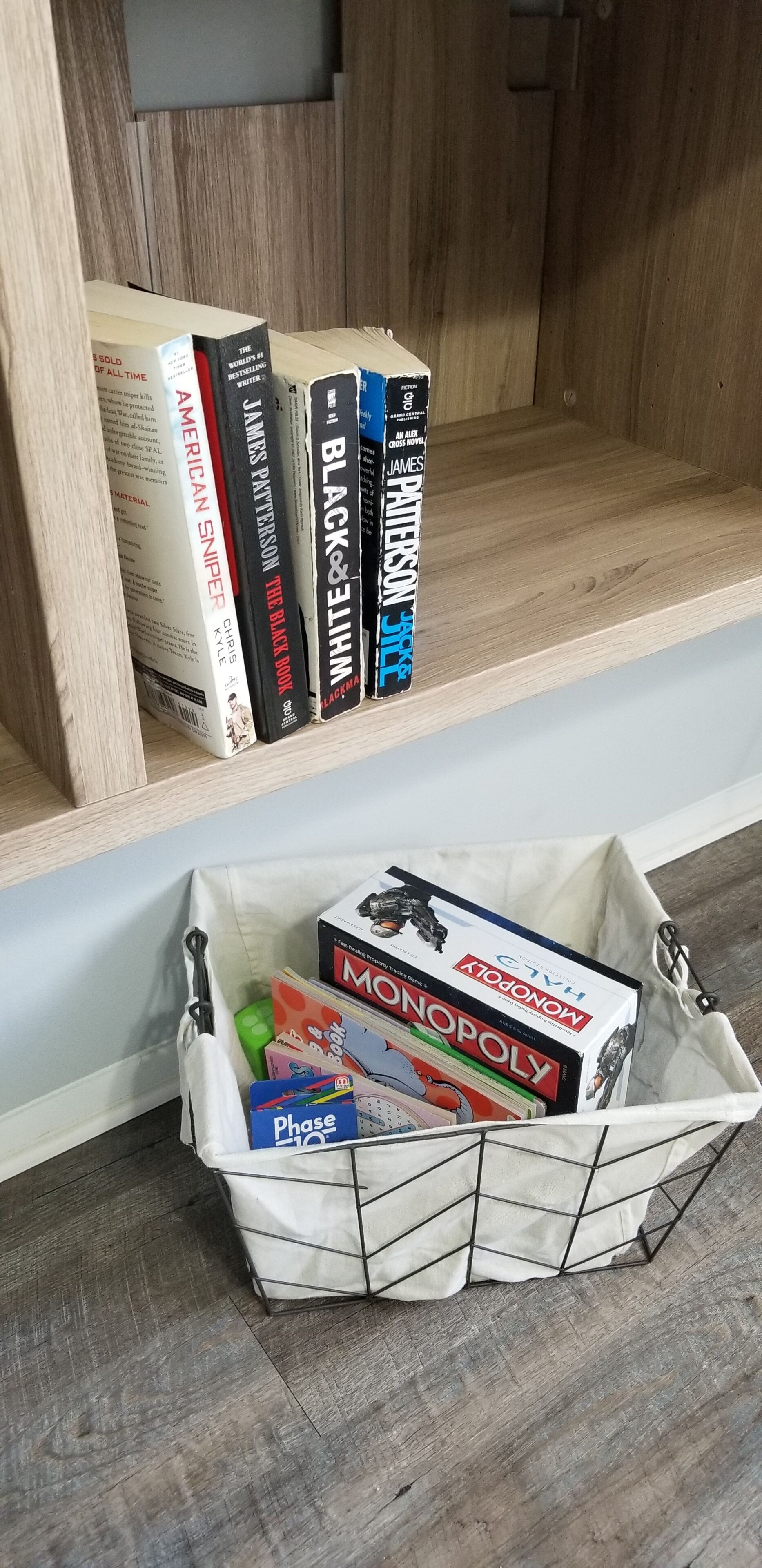 A bookshelf with books and a storage bin containing board games.