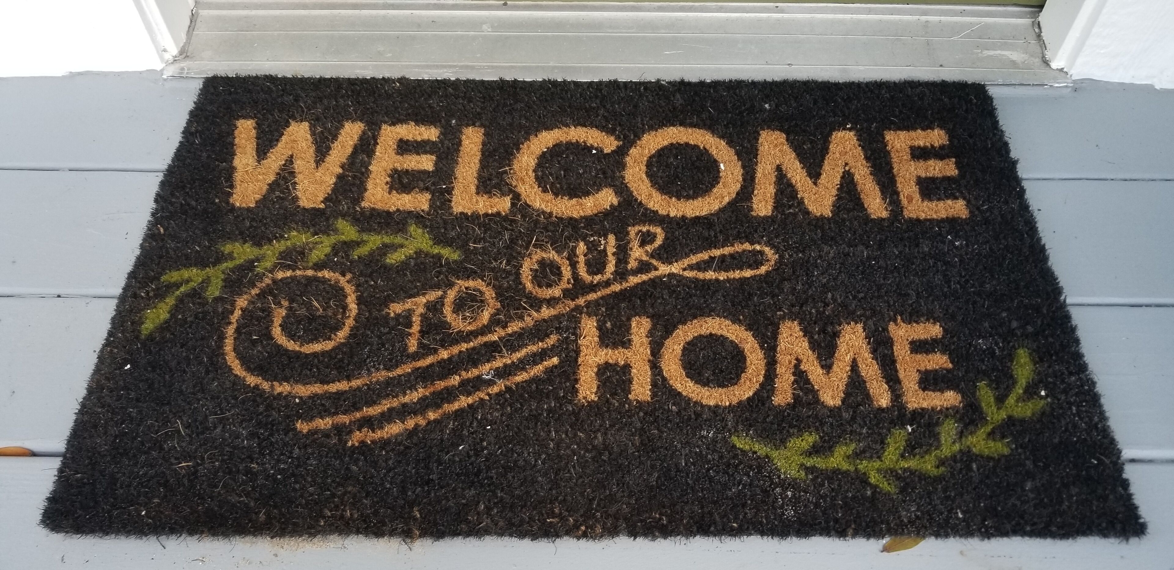 Un paillasson avec l’inscription « BIENVENUE CHEZ NOUS » dans une police décorative.