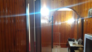 A wooden interior with a dining area, a TV, and a door leading to another room.