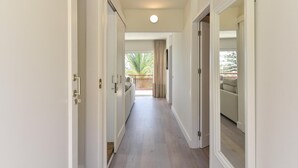 A hallway with a view to a balcony, a ceiling light, and a door on the left.