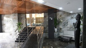 A lobby with a marble staircase, a white sofa, and a statue. - Kyriad Hotel Pimpri (Pune)