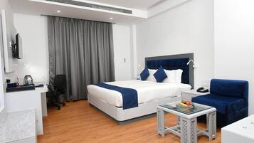 Une chambre d’hôtel moderne équipée d’un lit, d’un bureau, d’une chaise et d’une petite table sur laquelle se trouve des fruits.