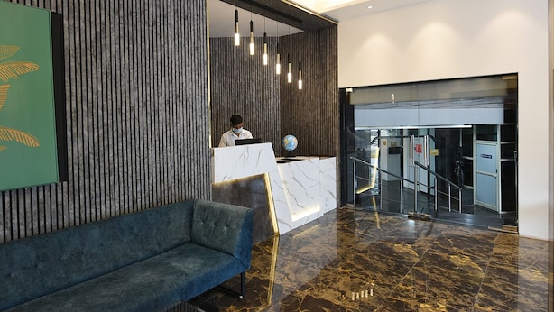 A modern reception area with a marble reception desk, a blue sofa, and a vertical wooden panel wall. - Kyriad Hotel Pimpri (Pune)