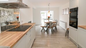 A modern kitchen with a central island, wooden flooring, and built-in appliances. - Daresfield (Cemaes Bay)