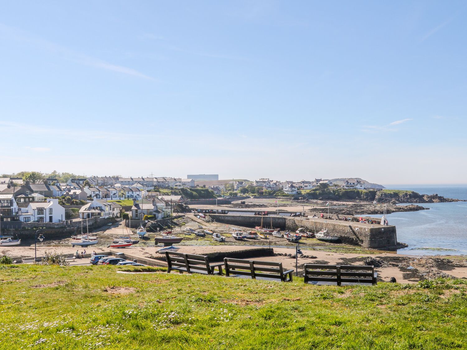 Une ville côtière dotée d’une structure fortifiée, d’une plage de sable et de bateaux.