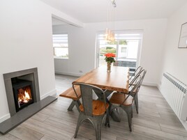 Comedor con chimenea, mesa de madera, sillas de metal y vistas al exterior.