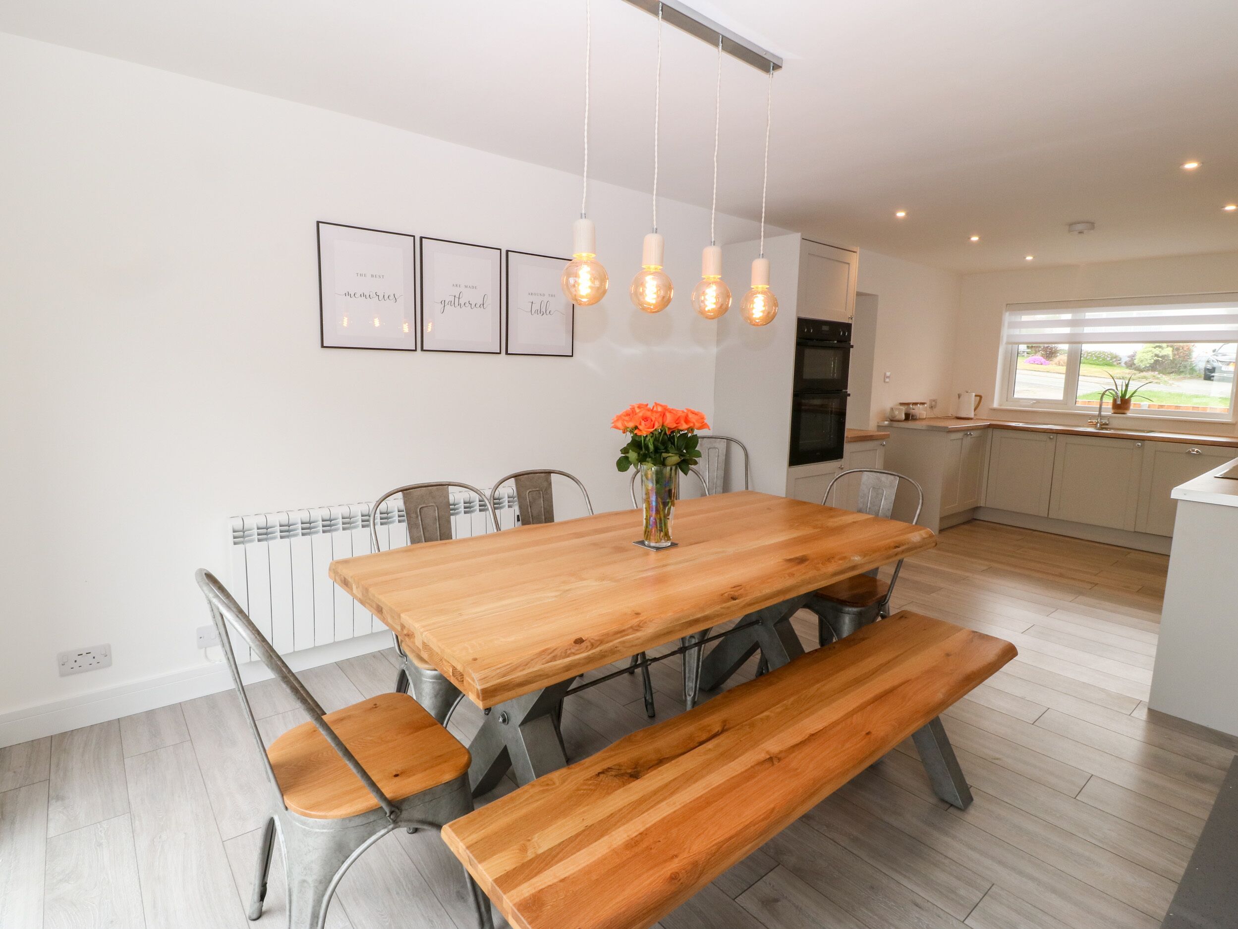 Un comedor con mesa de madera, bancos y un jarrón con flores.