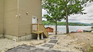 A house with a wooden deck and a stone pathway leading to a dock by a lake. - Lakefront Alton Bay Retreat w/ Dock Near Beaches! (Alton Bay)