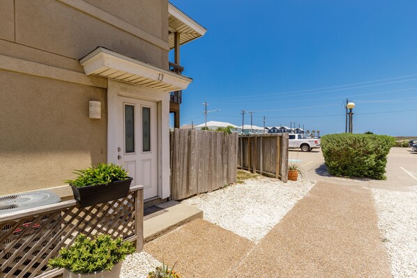 A residential building with a door, a balcony, and a gravel driveway. - Waterfront Escape | Pool & Fishing Dock Near Beach (6 night minimum) (Corpus Christi)