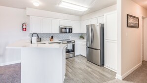 A modern kitchen with white cabinetry, stainless steel appliances, and a central island.
