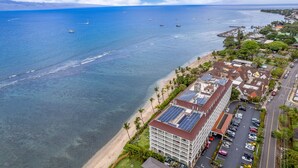 Vista aérea de un hotel costero con estacionamiento, playa y vista al océano.