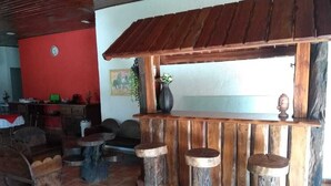 A rustic bar area with wooden stools and a wooden counter. - Pousada Por do Sol (Camanducaia)