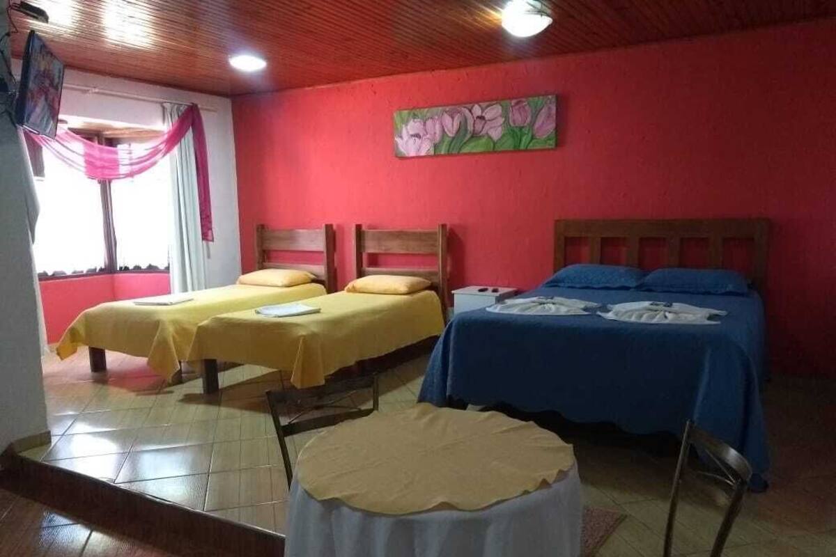 A room with two beds, a small round table, and a painting on the wall.
