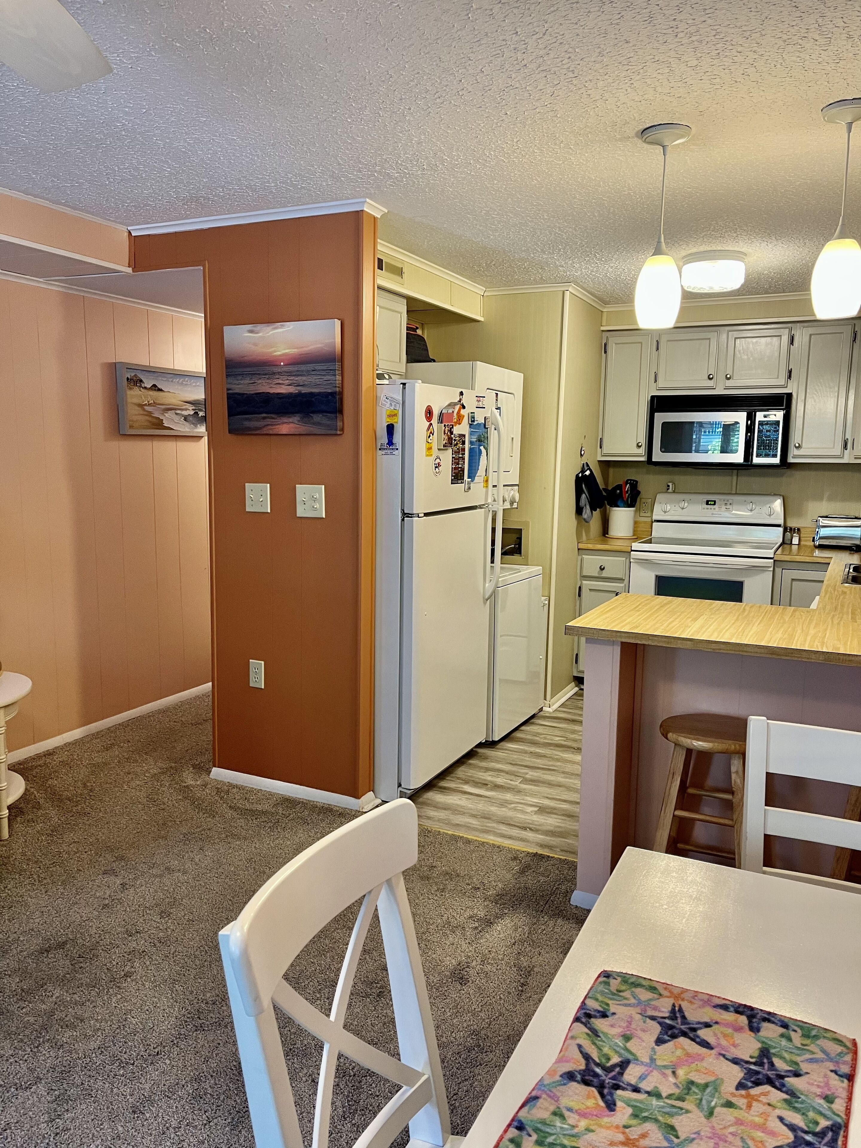 Cocina compacta con refrigerador, microondas y estufa.  Hay un comedor con mesa y sillas.