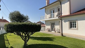 Ein zweistöckiges Haus mit einem Balkon, einem gepflegten Rasen und einem Baum.