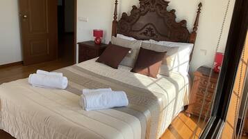A neatly made bed with a wooden headboard, a bedside table with a lamp, and a wooden nightstand.