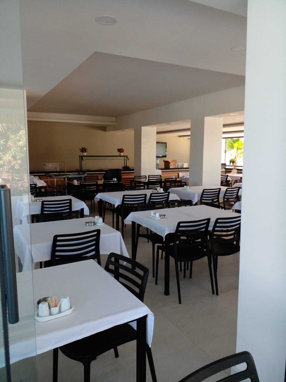 A restaurant with multiple tables and chairs, a counter area, and a view of the outdoors.