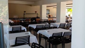 A restaurant with multiple tables and chairs, a counter area, and a view of the outdoors.