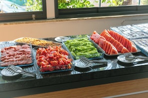 A buffet with various food options including sliced meats, tomatoes, green vegetables, and watermelon. - Palmila Butik Otel (Silifke)