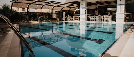 A swimming pool with clear water, a covered seating area, and a bar.