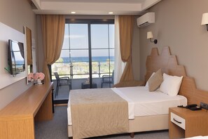 A hotel room with a large bed, a desk, a TV, and a view of the sea. - Palmila Butik Otel (Silifke)