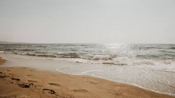 Una playa con huellas en la arena y olas acercándose a la orilla.