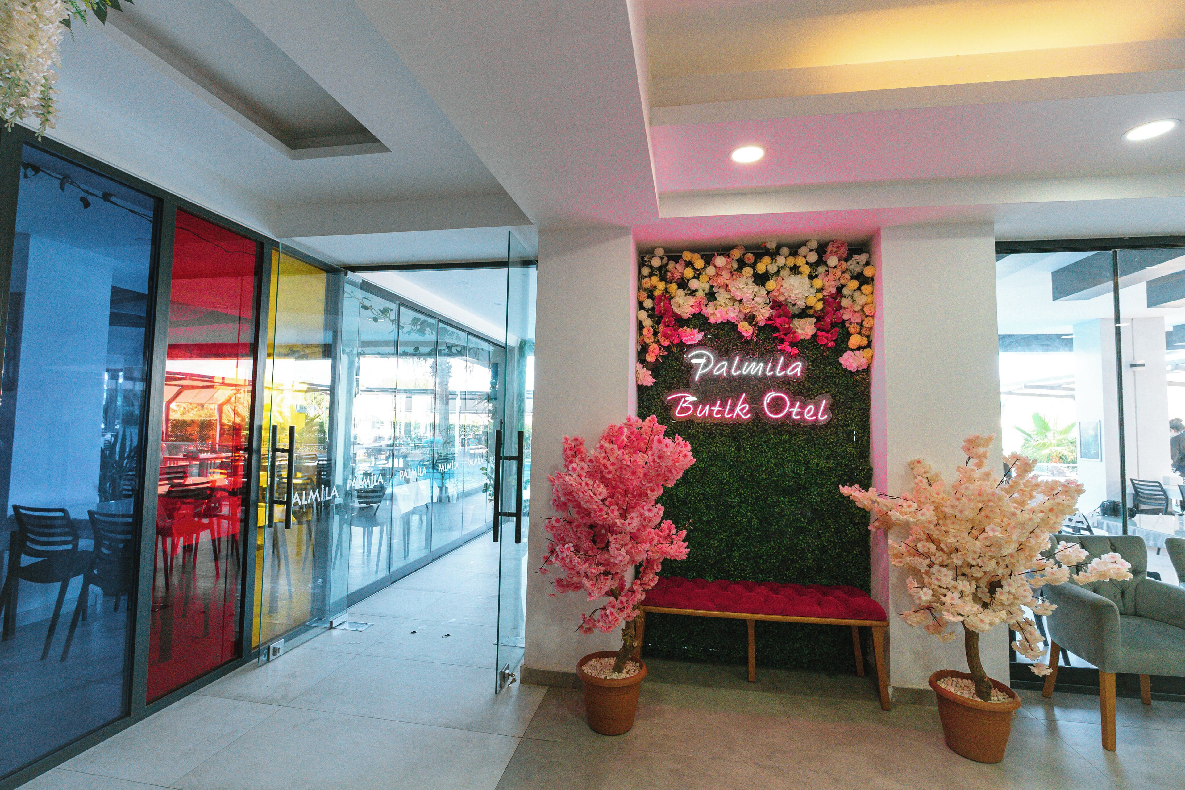Un hall de hotel con una recepción, una pared decorada con flores y un cartel que dice "Palmilia Boutique Hotel".