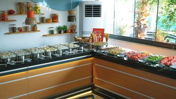 A buffet area with various food items and a window with a view of palm trees.